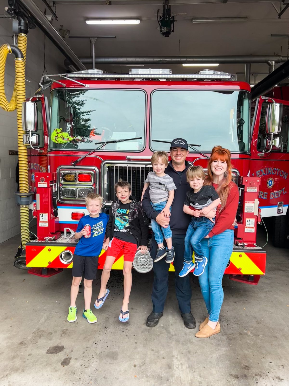 Stephanie with her firefighter husband and four boys in front of a Lexington fire truck
