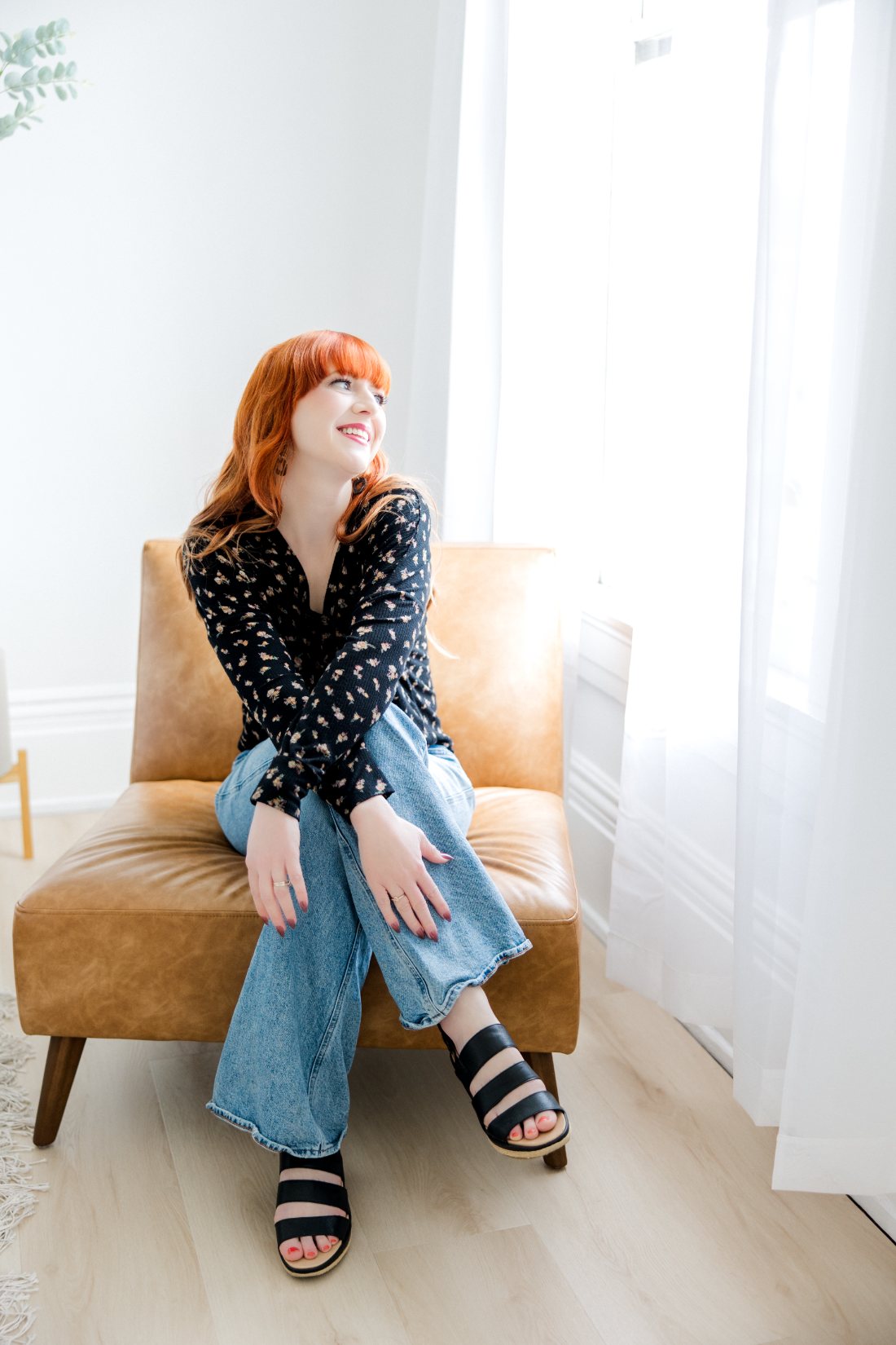 Stephanie sitting in a leather chair by the window